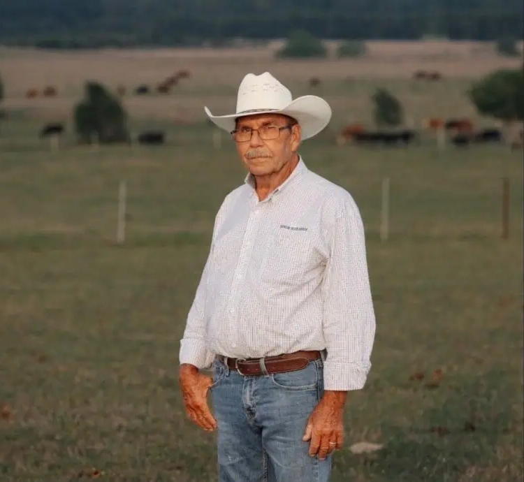 Herschel Cox, Ranch Manager at Sunday River Ranch, standing in a pasture with cattle behind him
